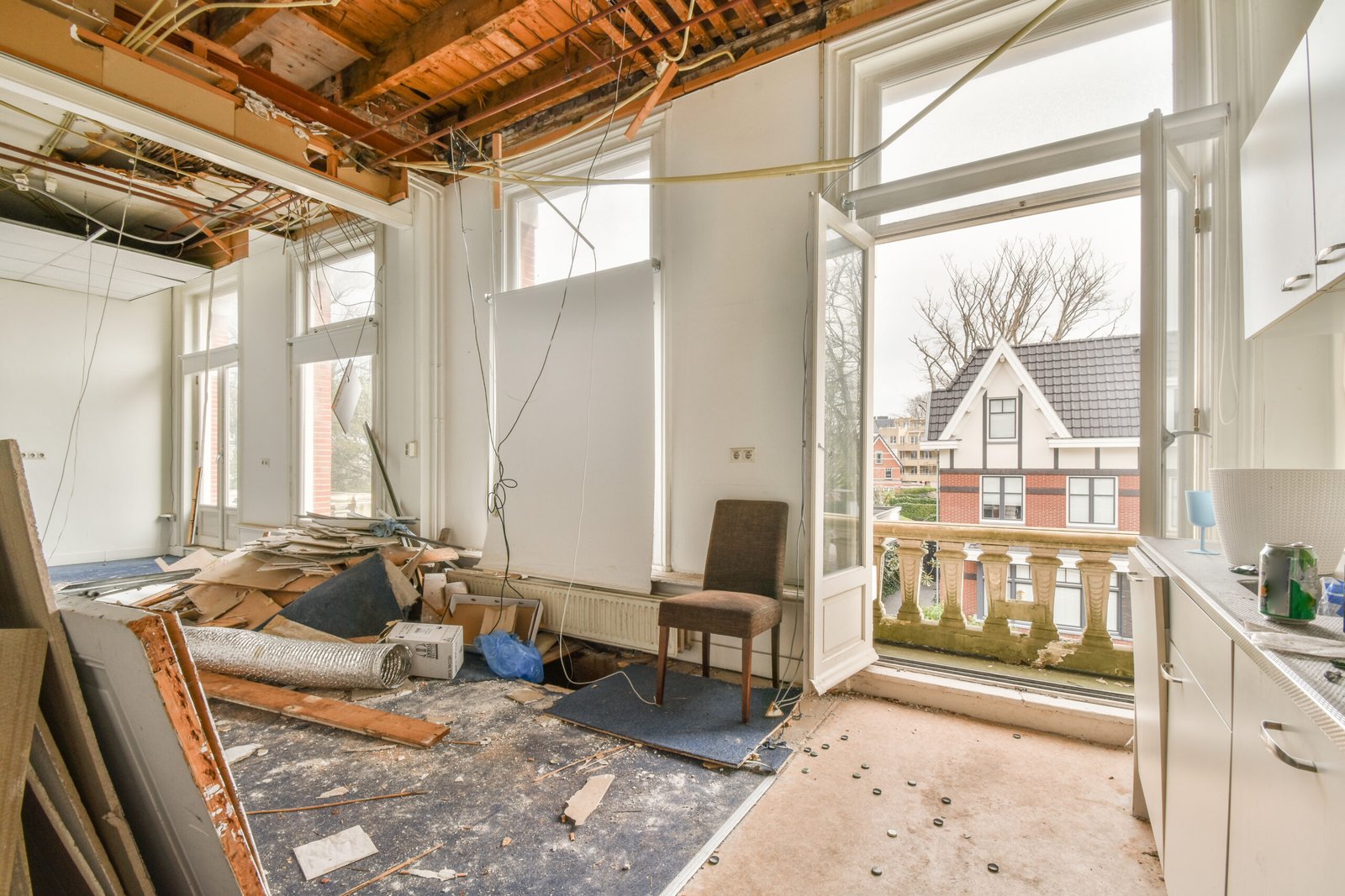 Interior of empty white room with large balcony windows with curtains and wooden parquet floor